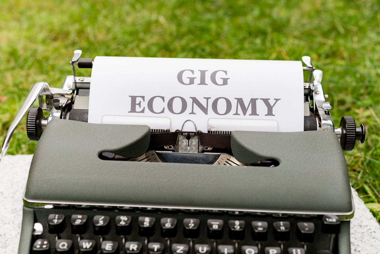 A vintage typewriter with 'Gig Economy' paper in an outdoor setting.